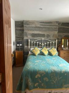 a bedroom with a bed with a stone wall at Yr Hen Fecws in Porthmadog
