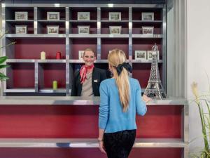a woman standing in front of a counter with a man at Mercure Cergy Pontoise Centre in Cergy