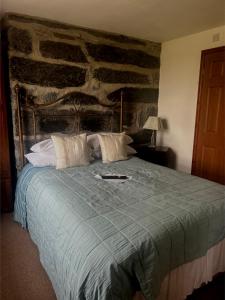 1 dormitorio con 1 cama con pared de piedra en Yr Hen Fecws en Porthmadog