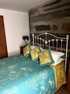 Un dormitorio con una cama con sábanas y almohadas azules y doradas en Yr Hen Fecws, en Porthmadog