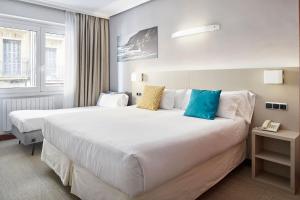 a hotel room with two beds and a phone at Hotel Parma in San Sebastián