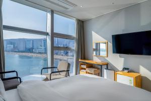 釜山にあるOceanstay Hotelのベッドと大きな窓が備わるホテルルームです。