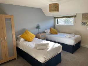 a bedroom with two beds with yellow pillows at Chequers Country Inn in Lutterworth