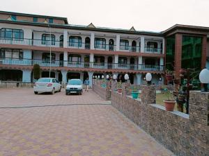 een groot gebouw met auto's geparkeerd op een parkeerplaats bij Hotel Kashmir Hilltown, Srinagar in Moniawār