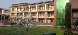 ein großes Gebäude mit Rasen davor in der Unterkunft Hotel Kashmir Hilltown, Srinagar in Moniawār