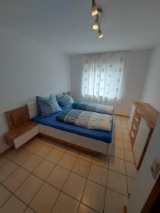Schlafzimmer mit einem Bett mit blauer Bettwäsche und einem Fenster in der Unterkunft Widmanns Ferienquartier in Wiehl