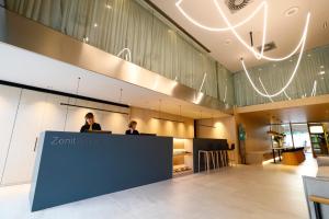 two people sitting at a counter in a lobby at Hotel Zenit Bilbao in Bilbao