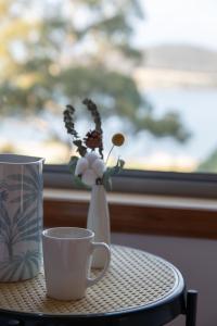 a table with a coffee cup and a vase with flowers at Sea View Guest House in Hobart