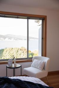a bedroom with a white chair and a large window at Sea View Guest House in Hobart