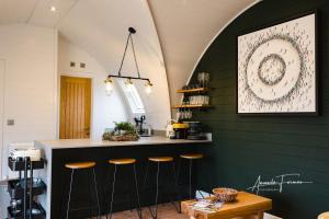 una cocina con una pared verde con taburetes de bar en Fallow Lodge, en Little Bytham