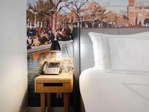 a hotel room with a bed and a phone on a table at Swissôtel Amsterdam in Amsterdam