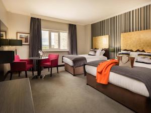 una camera d'albergo con due letti e una scrivania di Talbot Hotel Carlow a Carlow