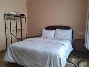a bed with white sheets and pillows in a room at Sabra Palmvillage mikocheni in Dar es Salaam +16 photos