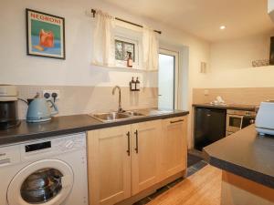 a kitchen with a sink and a washing machine at Waterside Cottage in Truro
