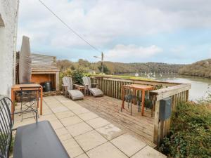 a deck with chairs and tables and a view of a river at Waterside Cottage in Truro