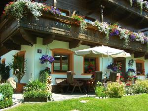 a house with a table and an umbrella and flowers at Schranbachhof in Maria Alm am Steinernen Meer