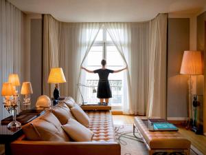 パリにあるホテル ラッフルズ ロイヤル モンソー パリの窓の外を見下ろすリビングに立つ女性