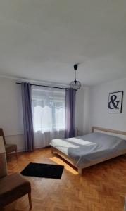 a bedroom with a bed and a window with purple curtains at Mieszkanie w domu jednorodzinnym in Człuchów