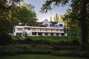 a large white house on a hill with trees at MolenVliet Vineyards in Stellenbosch