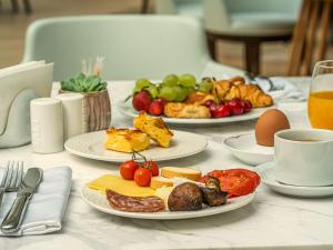 einen Tisch mit Teller mit Käse, Obst und Eiern in der Unterkunft Maison Sofia - MGallery in Sofia