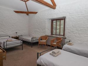 a room with three beds and two chairs and a window at Brimpts Barn in Yelverton