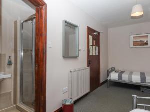 a bathroom with a glass shower and a bed at Brimpts Barn in Yelverton