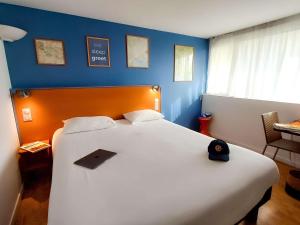 greet Hotel Belleville en Beaujolais A6 في بيللفيل سور-ساون: غرفة نوم بسرير ابيض كبير بجدار ازرق