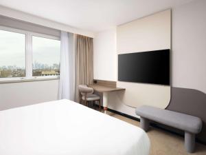 a hotel room with a bed and a desk and a television at Mercure London Earls Court in London
