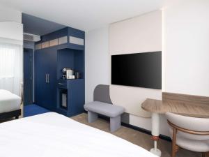 a room with a bed and a desk and a tv at Mercure London Earls Court in London