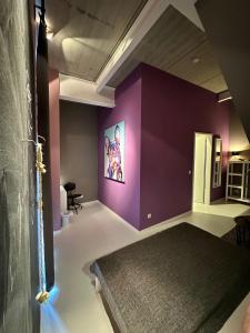 um quarto com uma parede roxa com uma cama em Guestroom by "FARBGESTALT" em Sarstedt