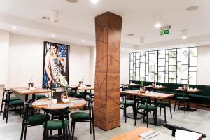 un restaurante con mesas de madera y sillas verdes en Ascot Premium Hotel, en Cracovia
