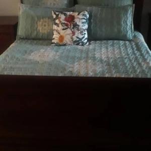 a bed with a blue comforter and a pillow at Inviting 3-Bed House in Bulawayo in Bulawayo