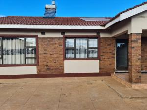 ein Backsteinhaus mit einer Eingangstür und Fenstern in der Unterkunft Inviting 3-Bed House in Bulawayo in Bulawayo