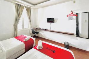 Habitación de hotel con 2 camas y escritorio en RedDoorz @ Best Hotel Jalan Dr. Sutomo Siantar en Pematangsiantar