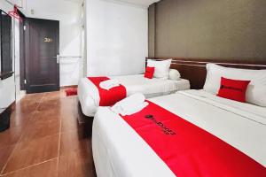 two beds in a room with red and white at RedDoorz @ Best Hotel Jalan Dr. Sutomo Siantar in Pematangsiantar