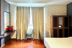 a bedroom with a bed and a chair and a window at RedDoorz @ Best Hotel Jalan Dr. Sutomo Siantar in Pematangsiantar +16 photos