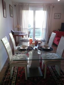 comedor con mesa de cristal y sillas blancas en Chambre Rafaël chez particulier, en Cherbourg-en-Cotentin