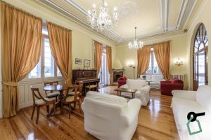 una sala de estar con muebles blancos y una lámpara de araña. en HOTIDAY Hotel Rapallo, en Rapallo