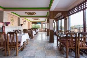 a dining room with tables and chairs and windows at Khumbila Hotel in Kathmandu