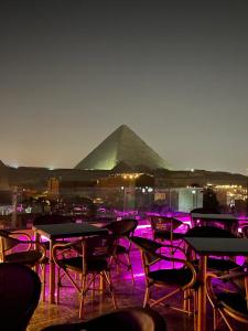 a group of tables and chairs with a pyramid in the background at Pyramids MAGIC INN in Cairo