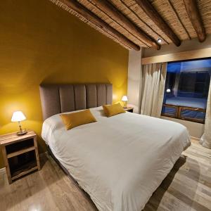 a bedroom with a large white bed and a window at Cabañas Bodega Kindgard in Purmamarca