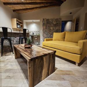 Cabañas Bodega Kindgard في بورماماركا: غرفة معيشة مع أريكة صفراء وطاولة قهوة خشبية