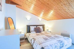 1 dormitorio con cama y techo de madera en Maison 5pers 10min à pied plage en LʼÉpine