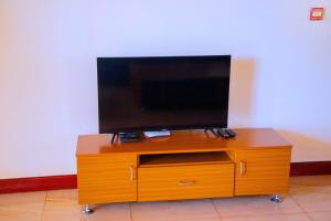 een flatscreen-tv op een houten entertainmentcentrum bij Kigali Village Suites in Kigali