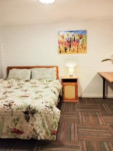 1 dormitorio con 1 cama, 1 mesa y 1 pintura en Koloona, en Wollongong
