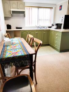 una cocina con armarios verdes, mesa y sillas en Koloona, en Wollongong