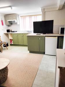 a kitchen with green cabinets and a flat screen tv at Koloona in Wollongong