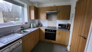 a kitchen with wooden cabinets and a sink and a microwave at Dean Edge in Cinderford