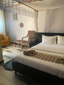 a bedroom with a large bed and a chair at Life Lounge Guest house in Mbarara
