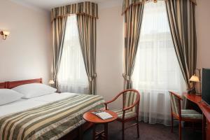a hotel room with a bed and a desk and two windows at Amigo City Centre in Prague